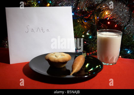 Kinder-Brief an den Weihnachtsmann ausgelassen am Heiligabend mit Mince Pie Karotte und ein Glas Milch vor Weihnachtsbaum Stockfoto