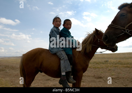 Geschwister fahren ihr Pferd zusammen in den mongolischen Steppen. Stockfoto