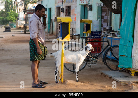 Inder sprechen auf öffentliches Telefon mit seiner Ziege. Yenumulapalli, Andhra Pradesh, Indien Stockfoto