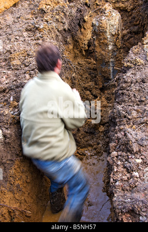 Arbeiter im aufgeweichten Boden aus Basis der Haufen entfernen Graben. Stockfoto