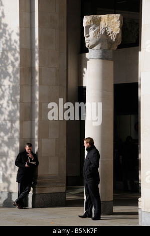 Zwei Männer stehen durch Engelsstatue in Ludgate Hill, Kirchhof St. Pauls Kathedrale, London, UK Stockfoto