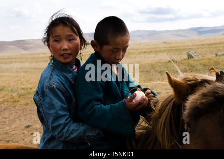 Geschwister fahren ihr Pferd zusammen in den mongolischen Steppen. Stockfoto