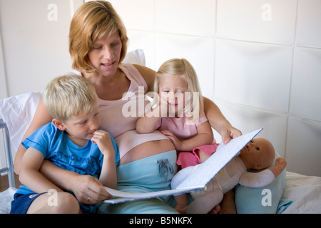 Schwangere Mutter liest ein Buch zu ihrem Sohn und Tochter Stockfoto