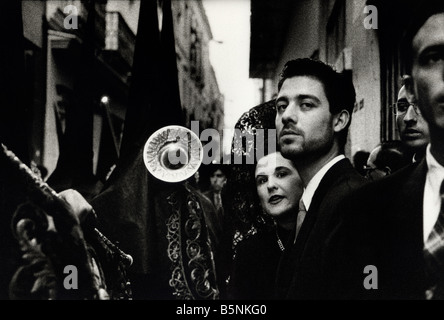Frau in traditioneller Kleidung mit Mann wie die Prozessionen der Semana Santa vorbeiziehen. Sevilla, Spanien Stockfoto