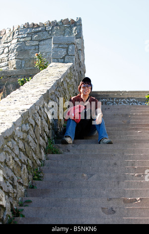 Chinesische Frau sitzen auf Stufen und lächelnd Stockfoto