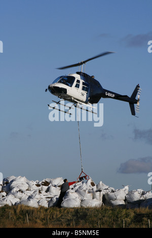 Helikopter-Hebekissen von Samen beladen Kompost für die Arbeiter, die Regeneration der Heide in der Nähe von Torside Reservoir in High Peak. Stockfoto