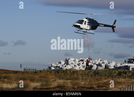 Helikopter-Hebekissen von Samen beladen Kompost für die Arbeiter, die Regeneration der Heide in der Nähe von Torside Reservoir in High Peak. Stockfoto