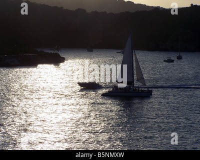 Ein Segelboot und andere Arten von Wasserfahrzeugen Silhouette gegen den Sonnenuntergang in einem schönen Karibik-Insel-Hafen in der Abenddämmerung. Stockfoto