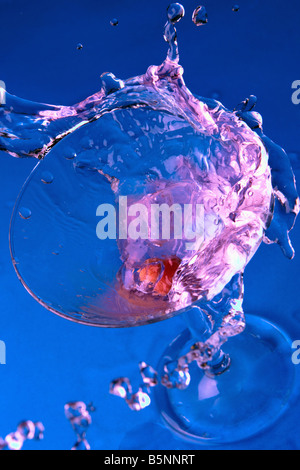 Cocktail im Glas mit Spritzern hautnah auf blauem Hintergrund Stockfoto