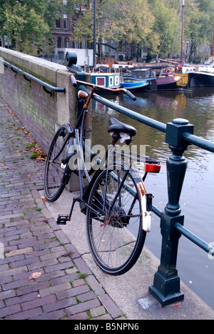 Einsames Fahrrad gesperrt auf Geländer über Brücke in Amsterdam-Niederlande-Europa Stockfoto