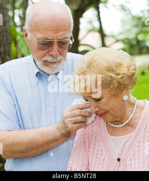 Traurige senior Frau weint, während ihr Mann ihre Tränen wischt konzentrieren sich auf die Frau Stockfoto