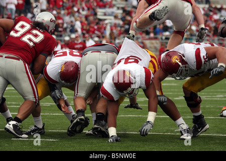 Eine defensive Lineman springt über ein beleidigender Störungssucher in einem College-Football (American Football)-Spiel. Stockfoto