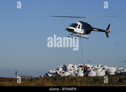 Helikopter-Hebekissen von Samen beladen Kompost für die Arbeiter, die Regeneration der Heide in der Nähe von Torside Reservoir in High Peak. Stockfoto