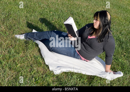 Eine junge Frau mit gesträhntes Haar, ein Buch lesen oder Hausaufgaben auf dem campus Stockfoto