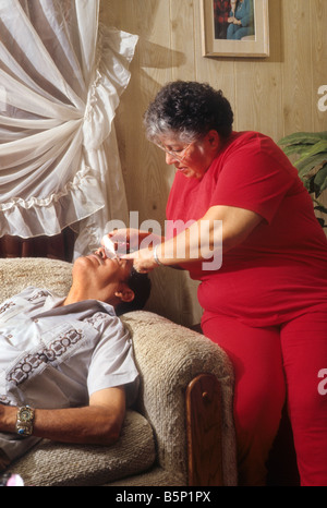 Hispanic Frau legt Augentropfen in die Augen des Mannes. Stockfoto