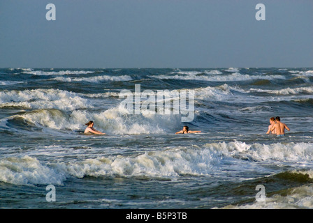 Menschen schwimmen an Seawall Boulevard Strand bei Sonnenaufgang in Galveston Texas USA Stockfoto