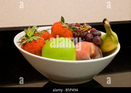 Nahaufnahme eines weißen Obstschale mit Apfel Erdbeeren Pfirsich Banane und Trauben Stockfoto
