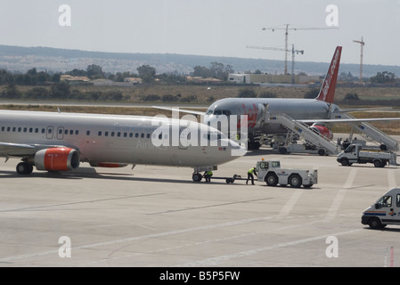 Bodenpersonal arbeiten im Scandinavian Airlines Flugzeug und ein Jet2 com Flugzeug auf dem Rollfeld des Flughafen Alicante Spanien Stockfoto