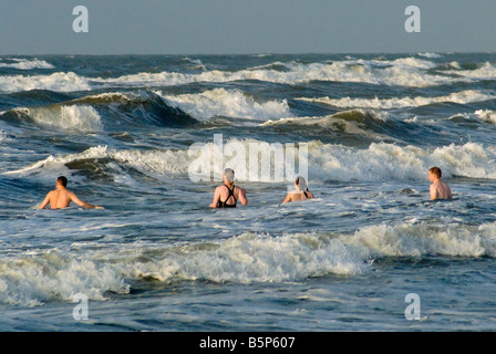 Menschen schwimmen an Seawall Boulevard Strand bei Sonnenaufgang in Galveston Texas USA Stockfoto