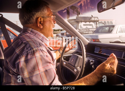 Verärgerter senior Mann hinter Rad des Autos Gesten und schreit ein anderer Fahrer. Stockfoto