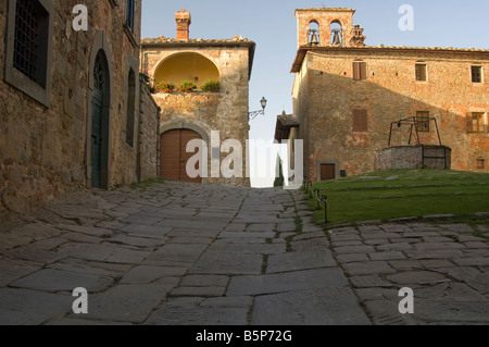 Sonnenaufgang am Gargonza in der Nähe von Monte San Savino wirft einen Schatten auf den mittelalterlichen Turm mit gepflasterten Pfad im Vordergrund. Stockfoto