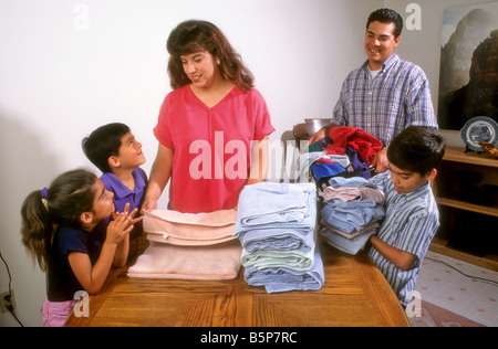 Hispanische Familie teilt sich in Falten Wäsche Hausarbeiten. Stockfoto