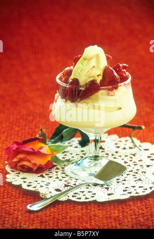 Vanille-Eis mit Beeren obendrauf, auf Deckchen mit Rose. Stockfoto