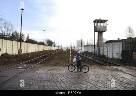 Die Berliner Mauer in Staaken am Ende des Kalten Krieges 1991.  Ein kleiner Junge mit dem Fahrrad zwischen den Bahnstrecken. Stockfoto