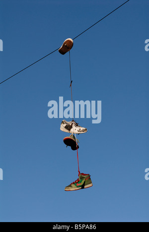 Alte Schuhe hängen aus dem Telefondraht Stockfoto
