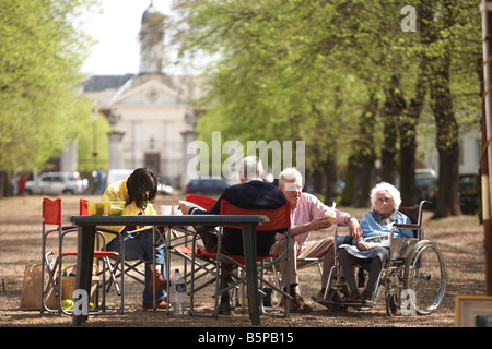 Ältere Dame wird von Familie an sonnigen Nachmittag in Chelseas grünen Royal Avenue SW3 mit Royal Hospital Chelsea in Ferne betreut Stockfoto