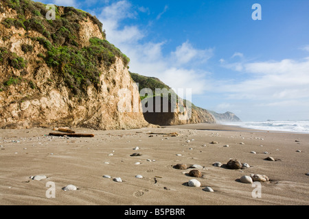 Runden Kieseln liegen in den Sand in einen wilden Strand unter steilen Klippen, Point Reyes National Seashore, Kalifornien. Stockfoto