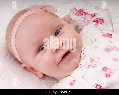 Babymädchen in rosa und weißen Kleid in die Kamera schaut. Stockfoto