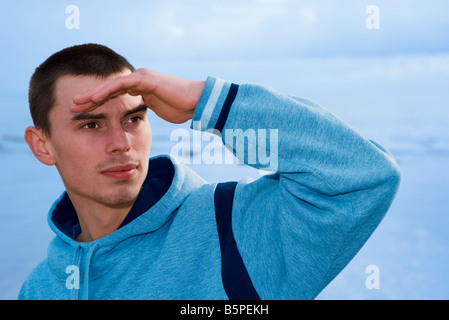 Junger Mann auf der Suche auf der Seite, die Augen vor Sonne Abschirmung Stockfoto