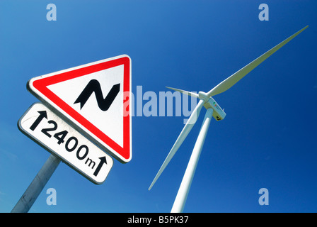 Kurven voraus Straßenschild in der Nähe einer Windturbine auf blauen Himmel - Frankreich Stockfoto