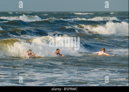 Menschen schwimmen an Seawall Boulevard Strand bei Sonnenaufgang in Galveston Texas USA Stockfoto