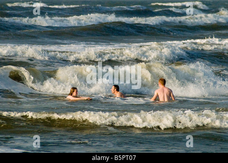 Menschen schwimmen an Seawall Boulevard Strand bei Sonnenaufgang in Galveston Texas USA Stockfoto