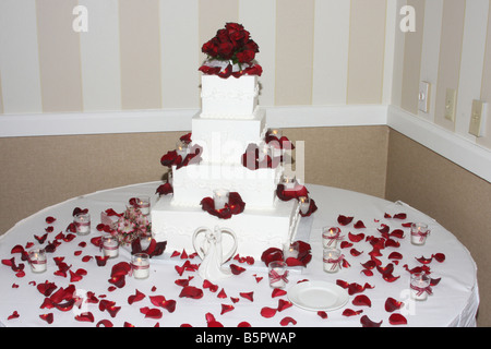 Eine ausgefallene Hochzeitstorte mit roten Rosen und Kerzen brennen um den Kuchen für eine Hochzeitsfeier angezeigt Stockfoto