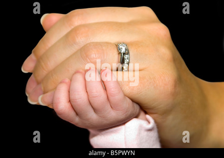 Horizontale Studio hautnah ein neugeborenes Baby Hand festhalten an einer Frau kleinen Finger gegen einen schwarzen Hintergrund. Stockfoto