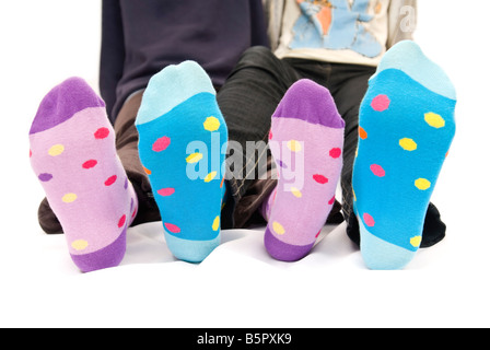 Horizontale Nahaufnahme von zwei Teenager Kinderfüße mit hellen farbigen fleckig Wintersocken auf weißem Hintergrund. Stockfoto