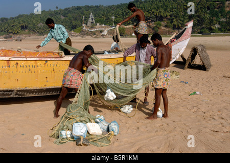 Fischer aus dem Dorf Chowara kümmern sich um Boote und Netze an Chowara Strand Nr. Trivandrum Kerela Staat Süd-Indien Stockfoto