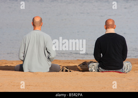 Zwei Männer praktizieren Yoga am Strand in Spanien Stockfoto