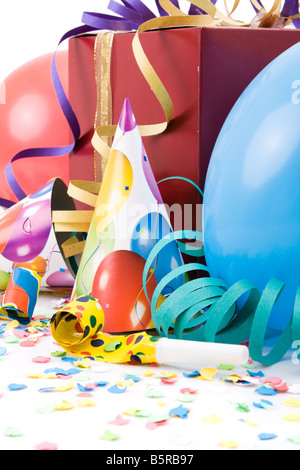 Geschenk, Partyhüte, Hörner oder Pfeifen, Confettis und Luftballons auf weißem Hintergrund. Stockfoto