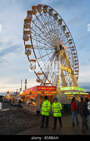 Polizisten vorbeigehen ein Riesenrad auf dem Jahrmarkt in der Nacht Stockfoto