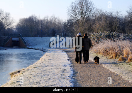 Wandern mit Hund auf dem Kanal Treidelpfad an einem frostigen Morgen Chesterfield Derbyshire paar Stockfoto