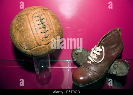 Ein altes Paar des Fußballs Stiefel Antik-Ledersohlen und Stollen mit einem alten Leder-Fußball im Nou Camp, Barcelona Katalonien Spai Stockfoto