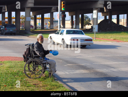 Afrikanische amerikanische Mann im Rollstuhl an belebten Kreuzung in amerikanischen Großstadt Stockfoto