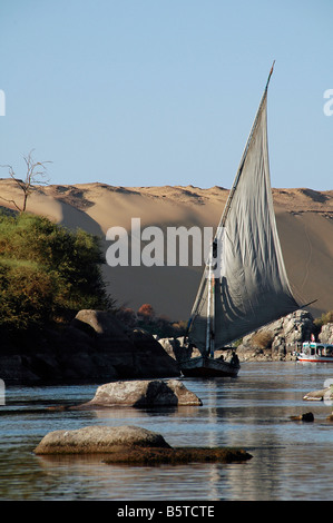 Felucca Traditionelles Boot, das entlang des Nils segelt, und der erste Katarakt mit der westlichen Wüste im Hintergrund in Assuan-Süditegypten Stockfoto