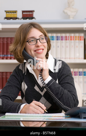 junge Frau mit Telefon im Büro Stockfoto