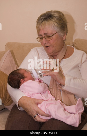 1 Woche alt Stutzflügel Tochter geboren Großmutter Person Frau füttern mit der Flasche neu Stockfoto