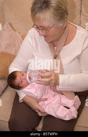 1 Woche alt Stutzflügel Tochter geboren Großmutter Person Frau füttern mit der Flasche neu Stockfoto